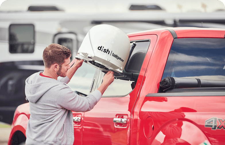 Person in gray hoodie connecting DISH Tailgater® to red truck.